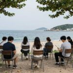부산 민락수변공원에서 열리는 부산바다도서관 야외 리딩존 사진, 바다와 하늘을 배경으로 다양한 의자에서 사람들이 책을 읽고 쉬고 있음