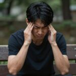 일사병 증상으로 두통과 어지럼증을 호소하는 사람이 그늘에서 휴식을 취하고 있다