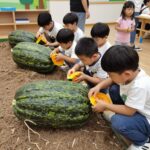 어린이집 초복 이벤트 아이디어와 실제 사례 어린이집 초복 이벤트 포토존에서 아이들이 수박을 들어보는 모습