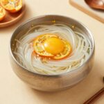 콩가루 콩국수 만드는 방법 5분 완성 콩가루로 만든 시원한 콩국수 그릇에 오이와 계란 고명이 올려져 있다