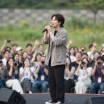 트로트 가수 남궁진이 야외 공연장에서 무대 위에서 노래하는 모습. 관객들이 환호하는 가운데 열정적으로 마이크를 잡고 있다.